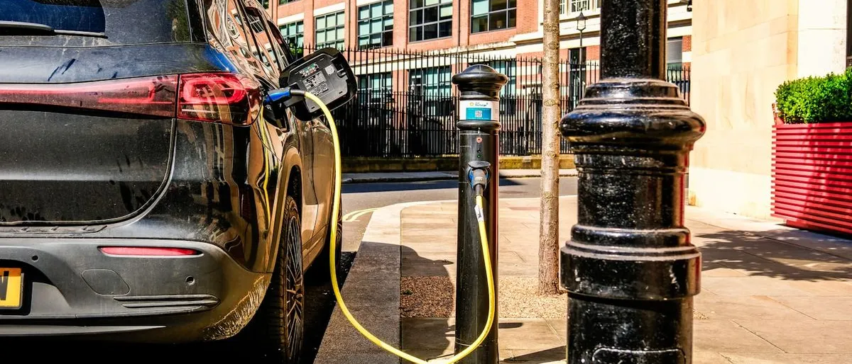Un véhicule électrique en charge sur une borne de rue, câble branché à l'arrière du véhicule.